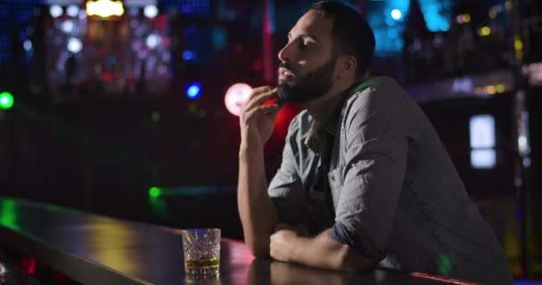 Portrét depresivního osamělého muže ze Středního východu stojícího vedle baru a popíjejícího ze skla v nočním klubu. Jeden pohledný chlapík tráví večer sám. Cinema 4k Prores Hq. — Stock video