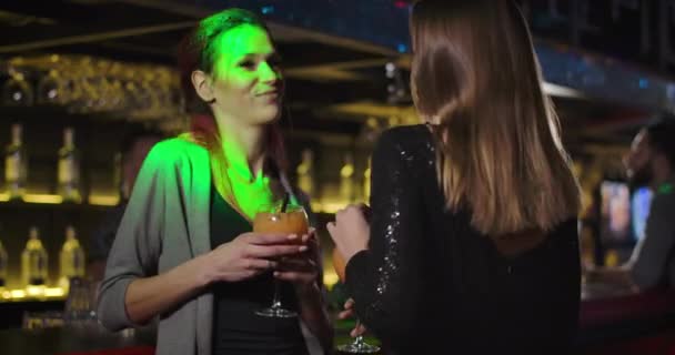 Primer plano de dos jóvenes y alegres mujeres caucásicas bailando con cócteles y hablando en un club nocturno. Chicas felices saliendo y bebiendo alcohol. Ocio, entretenimiento, estilo de vida. Cine 4k proRes HQ . — Vídeos de Stock