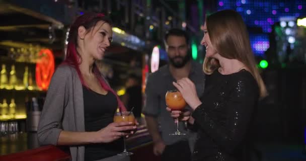 Bliskowschodni mężczyzna przychodzący do dwóch młodych białych kobiet pijących koktajle w nocnym klubie. Pewny siebie przystojniak flirtujący z dziewczynami w dyskotece. Kino 4k Prores Hq. — Wideo stockowe