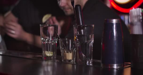 Two blurred professional bartenders adding spices and lemons to cocktails. Young Caucasian men preparing drinks for visitors in night club. Alcohol, bar counter. Cinema 4k proRes HQ. — 비디오