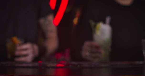 Two male bartenders putting glasses with cocktails on bar counter. Close-up of mixed drinks in night club. Cinema 4k ProRes HQ. — Stok video