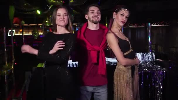 Jonge blanke mooie vrouwen en knappe man poserend in nachtclub. Positieve mannelijke Dj knuffelen vrolijke vrouwelijke go dansers staan in disco met de handen gekruist. Lifestyle, rusten, entertainment. — Stockvideo