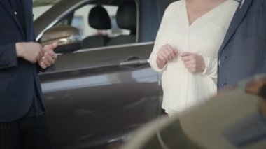 Tanımlanamayan olgun, sarışın, beyaz kadın torbacıdan araba anahtarlarını alıyor ve kocasına sarılıyor. Şen şakrak yaşlı bayanın galeride hediye olarak yeni bir araç alması. Neşe, başarı, yaşam tarzı, zenginlik.