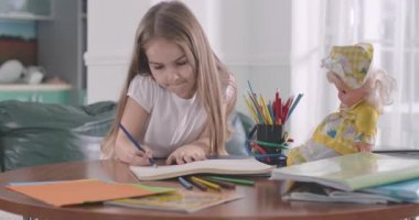 Evde ödev yapan Kafkasyalı zeki öğrencilerin yakın çekimi. Okulda öğrendikleri oyuncak bebek malzemelerini açıklayan bir çocuk. Eğitim, zeka, öğrenim kavramı. Sinema 4k ProRes Merkezi.