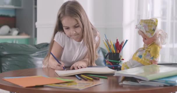 Close-up van slimme blanke schoolmeisjes die thuis huiswerk maken. Kind legt haar poppenmateriaal uit dat ze op school leren. Plezier in het onderwijs, intelligentie, studeren concept. Cinema 4k ProRes Hoofdkwartier. — Stockvideo