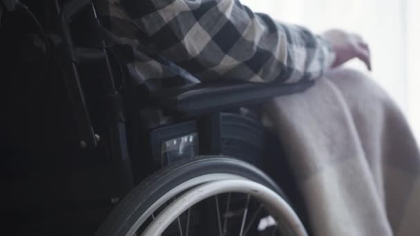Primer plano de la silla de ruedas con el viejo hombre caucásico discapacitado sentado en ella. Tipo paralítico maduro usando equipo para el movimiento. Discapacidad, vejez, estilo de vida . — Vídeos de Stock