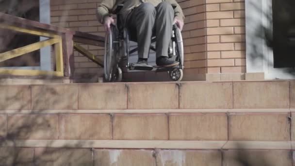 Tanımlanamayan yaşlı, tekerlekli sandalyedeki beyaz adam merdivenlerden inip duruyor. Engelli birinin aşağı inme şansı yok. Rampa erişilebilirliği, engellilik sorunları. — Stok video