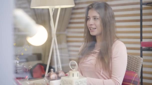 Retrato de una joven mujer caucásica confiada hablando con alguien en el restaurante. Linda chica morena sentada en el café en una cita romántica, disparando a través de cristal de la ventana. Amor, estilo de vida, romance, elegancia — Vídeos de Stock