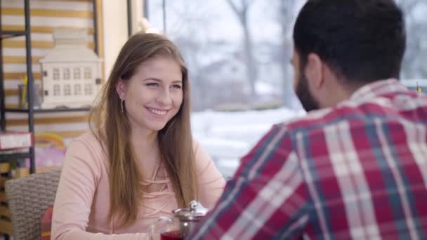 Porträtt av ung brunett vit kvinna ler och ser med intresse på Mellanöstern pojkvän talar. Söt positiv tjej dejta med pojkvän i caféet. Romans, kommunikation, livsstil. — Stockvideo