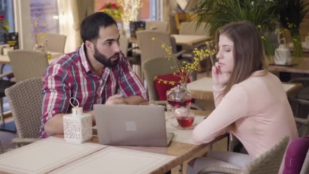 Portret van een jonge blanke vrouw en een man uit het Midden-Oosten die zakenluncht in een café. Succesvolle mensen die zaken doen in een restaurant. Samenwerking, teamwork, partnerschap. — Stockvideo