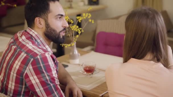 Takapuolella näkymä komea Lähi-idän mies puhuu ja etsii rakkaudella tunnistamaton tyttöystävä tai vaimo ravintolassa. Nuori monietninen pari dating kahvilassa. Onnellisuus, ilo, romanssi . — kuvapankkivideo