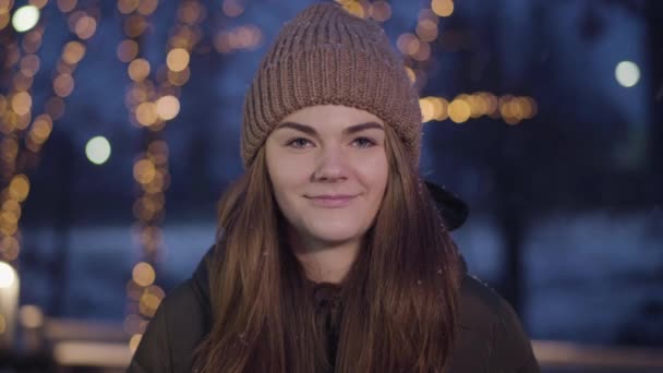 Portrait of positive young Caucasian girl getting snowball on face outdoors. Beautiful brunette woman with grey eyes playing snowballs with friends. Winter fun, leisure games, snowball fight. — Stock Video