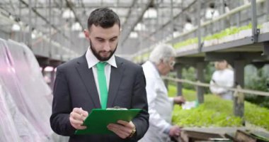 Genç, beyaz sakallı bir adam olgun, bulanık bir tarımcı istiyor ve bilgi yazmak için dönüyor. Glasshouse 'da organik sebze üreten kendine güvenen bir denetçi. Sinema 4k ProRes Merkezi.