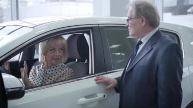 Şık, üst düzey, beyaz bir çift galeriden yeni araba alıyor. Takım elbiseli bir adam ve gözlüklü bir adam salonda oturmuş karısıyla konuşuyor ve torbacıların elini sıkıyor. Yaşam tarzı, iş hayatı, başarı.