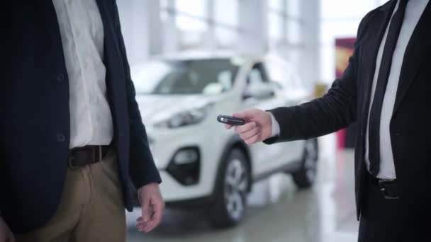 Due irriconoscibili caucasici in giacca e cravatta che passano le chiavi dell'auto davanti al veicolo nuovo. Uomo d'affari di successo l'acquisto di automobili in concessionaria auto e agitazione commercianti mano. Industria, imprese . — Video Stock