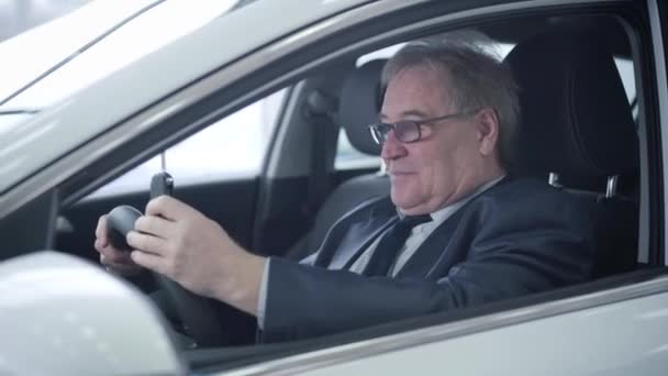 Close-up retrato de homem branco maduro positivo olhando pela janela do carro e se gabando chaves. Homem sênior sorrindo comprando veículo na concessionária de carros. Sucesso, indústria automobilística, sala de exposições de automóveis . — Vídeo de Stock