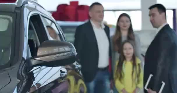 Έμπορος δίνει κλειδιά από το νέο μαύρο αυτοκίνητο στην ευτυχισμένη ιδιοκτήτες στην αντιπροσωπεία. Επιτυχημένος επιχειρηματίας χειραψία εμπόρους, την αγορά του οχήματος για την οικογένεια. Επικεντρώθηκε στο αυτοκίνητο. Κινηματογράφος 4k ProRes HQ. — Αρχείο Βίντεο