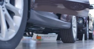 Kotlu beyaz kadın ayakları ve otomobilden çıkan siyah yüksek topuklu ayakkabılar. Kendine güvenen bir kadın araba galerisinde yeni alınmış bir aracın yanında duruyor. Sinema 4k ProRes Merkezi.
