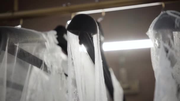 Close-up de cabides com vestidos de luz semitransparentes brancos na boutique. Roupas penduradas no centro comercial. Moda, beleza, estilo . — Vídeo de Stock