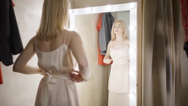 Slowmo de jeune femme blanche élégante regardant la réflexion dans le vestiaire. Femme riche confiante essayant sur la robe dans la boutique de mode. Shopping, mode de vie, beauté. Mouvement lent . — Video