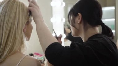 Sarışın beyaz kadın için makyaj yapan kadın vizecinin yakın çekimi. Güzellik salonunda zengin müşterilere hizmet eden profesyonel esmer kız. Yaşam tarzı, moda, güzellik. Yavaş çekim.