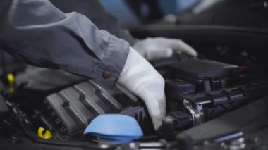 Beyaz koruyucu eldivenli erkek elleri arabanın içini kontrol ediyor. Otomatik tamirci kaputu elle inceliyor. Araç bakımı, benzin istasyonu, otomotiv endüstrisi, akort.