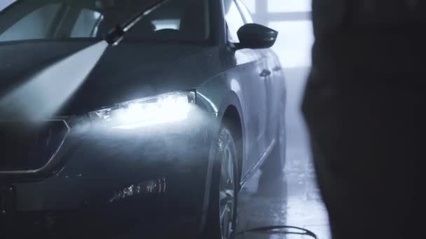 Primer plano de lavado de coches en la tienda de cuidado de automóviles. Vehículo de limpieza de empleados irreconocible manualmente con equipo de alta presión para pulverización de agua . — Vídeos de Stock