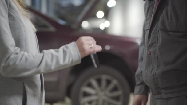 Mão branca fêmea que passa chaves do carro ao mecânico masculino do automóvel na oficina de reparação. Mulher irreconhecível deixando o automóvel para sintonizar na estação de serviço. Manutenção, indústria automóvel . — Vídeo de Stock