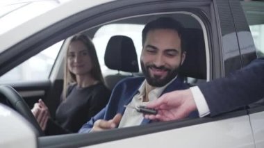 Gülümseyen Orta Doğulu bir adamın portresi araba anahtarlarını satıcıdan alıp heyecanlı karısına veriyor. Minnettar eş yakışıklı kocaya sarılıyor. Varlıklı aile galeride yeni bir araçta oturuyor..