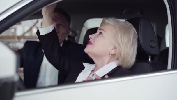 正面的高级白人女性与交易者一起检查汽车内部的侧视图。成功的富有客户选择汽车经销商。生活方式，商业，富裕，奢侈. — 图库视频影像