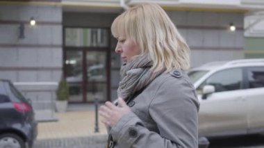 Kalbinde keskin bir ağrı olan olgun, beyaz bir kadının yakın plan görüntüsü. Yaşlı emekli, şehir caddesinde yürüyor ve bankta kalp ağrısı çekiyor. Yaşam tarzı, kalp krizi, sağlık hizmetleri..