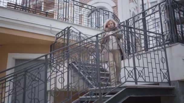 Mujer caucásica seria mirando el reloj y corriendo por las escaleras al aire libre. Un jubilado seguro y elegante que se va a una reunión. Estilo de vida, negocios, personas mayores activas, éxito . — Vídeo de stock