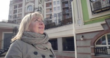 Son sınıf Kafkas kadınının yabancı şehirde hayranlık uyandıran görüntüleri. Güneşli bir sokakta durup etrafa bakınan pozitif gülümseyen emekli. Turizm, mutluluk, yaşam tarzı. Sinema 4k Prores Merkezi.