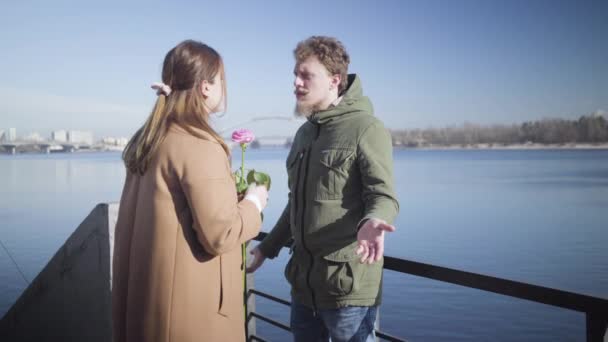 Mladý bělošský pár se hádá venku. Nervózní baculatá dívka, vracející růžovou k muži a odcházející. Problémy se vztahem, konflikty, životní styl. — Stock video