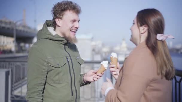 快乐的年轻女人用冰淇淋和笑声触摸男人的鼻子。积极的白人夫妇在阳光明媚的秋日户外约会的肖像。快乐，生活方式，团结，快乐. — 图库视频影像