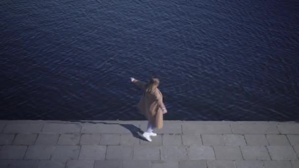 Vista dall'alto di allegra giovane donna caucasica che gira sulla riva del fiume. Ampio colpo di felice paffuto ragazza godendo giornata di sole all'aperto. Felicità, stile di vita, gioia, svago . — Video Stock