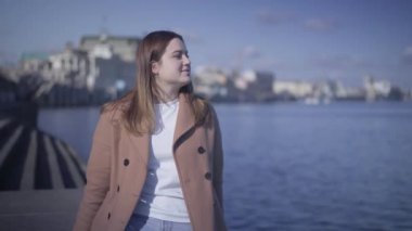 Mutlu genç tombul kız güneşli bir sonbahar gününde su dalgalarına bakıyor. Esmer, beyaz bir kadın nehir kıyısında dinlenirken gülümsüyor. Boş zaman, huzur, yaşam tarzı..