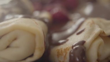 Fırında krep üzerine çikolata damlatan yakın çekim. Tabağında böğürtlen ve şurup olan lezzetli bir tatlı. Shrove Salı, yemek, yemek, fırın.