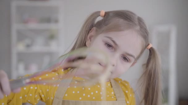 Close-up gezicht van mooie blanke meisje kijken naar mengsel druipt uit de garde. Schattig klein kind pannenkoeken bakken voor Shrove Tuesday. Lifestyle, koken, eten, Shrovetide. — Stockvideo
