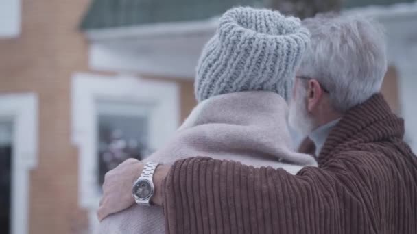 Gros plan arrière vue du couple marié heureux avec différence d'âge regardant la nouvelle maison le jour de l'hiver. Homme caucasien âgé confiant étreignant son conjoint et parlant à l'extérieur. Joie, mode de vie, propriété . — Video