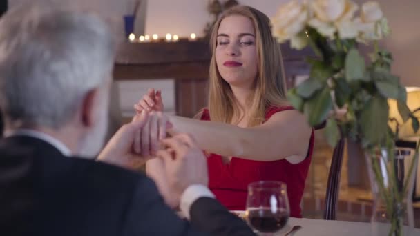 Portret van een mooie jonge vrouw die de hand reikt aan een oudere man. Onherkenbare zakenman die een trouwring om haar vinger doet. Gelukkig opgewonden meisje glimlachend naar liefhebbende partner. Aanzoek, liefde, romantiek. — Stockvideo