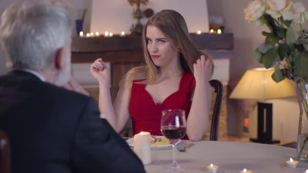 Verleidelijke jonge brunette vrouw aanraken van haar en lichaam als kijken naar onherkenbare senior man zitten voor haar aan de tafel. Vrouw van eenvoudige deugd verleiden middelbare leeftijd zakenman. — Stockvideo