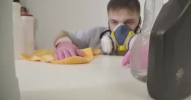 Beyaz bir erkek eli koruyucu eldivenlerle deterjanla masaları temizliyor. Arka planda maske takmış mobilyaları ovuşturan bulanık bir genç. Oda servisi, ev işi. Sinema 4k Prores Merkezi.