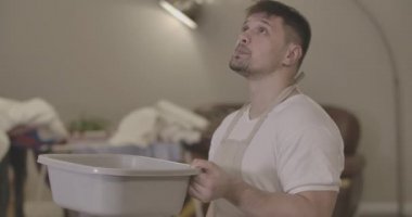 Kafkasyalı genç bir adam leğen tutuyor ve sızdıran tavana bakıyor. Kovası olan yakışıklı bir adamın ev ile ilgili sorunları var. Su hasarı, tamirat, temizlik. Sinema 4k Prores Merkezi.