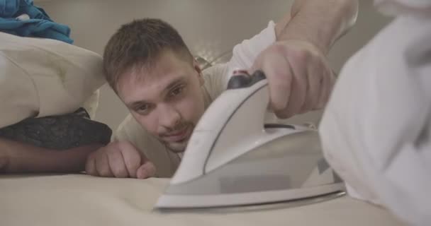 Young confident Caucasian man ironing clothes indoors. Portrait of brunette handsome guy doing housework. Focused on person face. Housekeeping, lifestyle, household. Cinema 4k ProRes HQ. — Stock Video