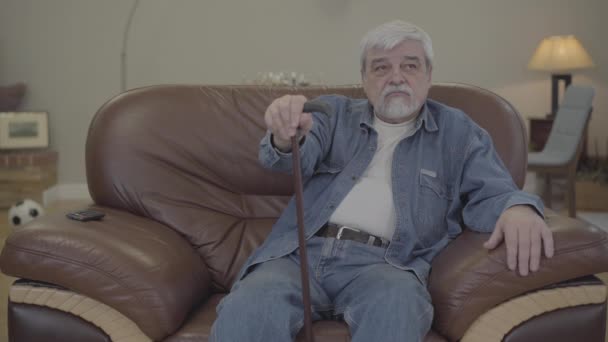 Unrecognizable Caucasian man helping senior retiree to stand up. Portrait of mature Caucasian father with walking stick leaving with attentive adult son. Support, care, lifestyle. — Stock Video