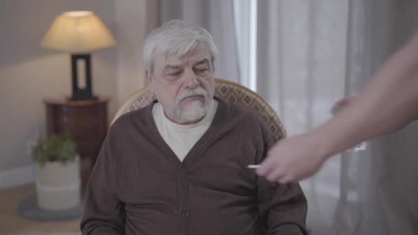 Retrato de un viejo caucásico irritado que se niega a tomar medicamentos. Primer plano del jubilado masculino mayor haciendo un gesto no agitando la cabeza y saludando con la mano. Salud, hogar de ancianos, envejecimiento . — Vídeo de stock