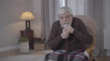 Kafkasyalı üzgün yaşlı adamın portresi iç çekiyor ve başka tarafa bakıyor. Üzgün erkek emekli evde yalnız bir akşam geçiriyor. Sosyal sorunlar, yaşlanma, emeklilik, yalnızlık, yaşam tarzı.
