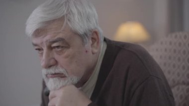Çaresiz Kafkas ihtiyarının iç çekişini yakından çek. Kahverengi gözlü gri saçlı emeklinin portresi evde yalnız zaman geçiriyor. Depresyon, yalnızlık, yaşam tarzı, yaşlanma.