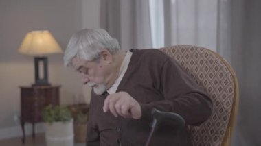 Olgun beyaz adamın portresi etrafa bakınıyor, mataradan alkol içiyor ve geri saklıyor. Yaşlı emekli erkek, hiçbir şey olmamış gibi koltukta oturuyor. Yaşlanma, yaşam tarzı, sağlık hizmetleri.